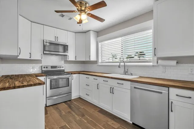 a kitchen with granite countertop a sink stainless steel appliances and white cabinets
