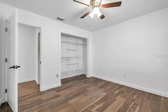 an empty room with wooden floor closet and windows