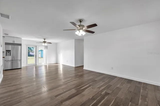 a view of an empty room with window and wooden floor