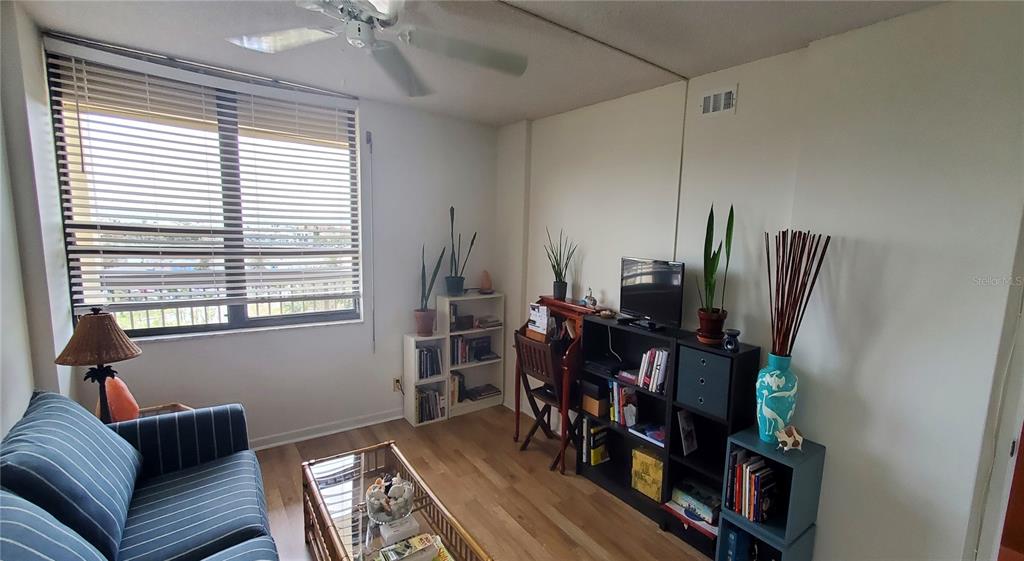 9415 Blind Pass Road, Unit 905 St. Pete Beach, FL 33706 - Photo 23 of 51 a living room with furniture a bookshelf and a window