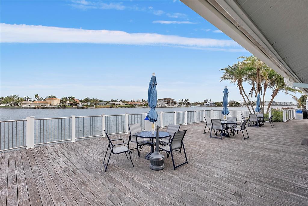 9415 Blind Pass Road, Unit 905 St. Pete Beach, FL 33706 - Photo 33 of 51 a view of a roof deck with table and chairs a barbeque with wooden floor and fence