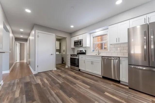 a kitchen with a refrigerator a stove top oven and white cabinets