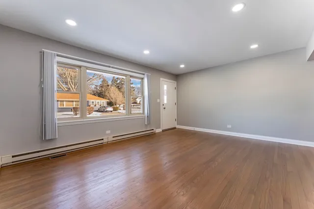 an empty room with wooden floor and window
