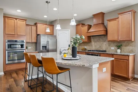 a kitchen with stainless steel appliances granite countertop a kitchen island a stove a sink cabinets and a dining table