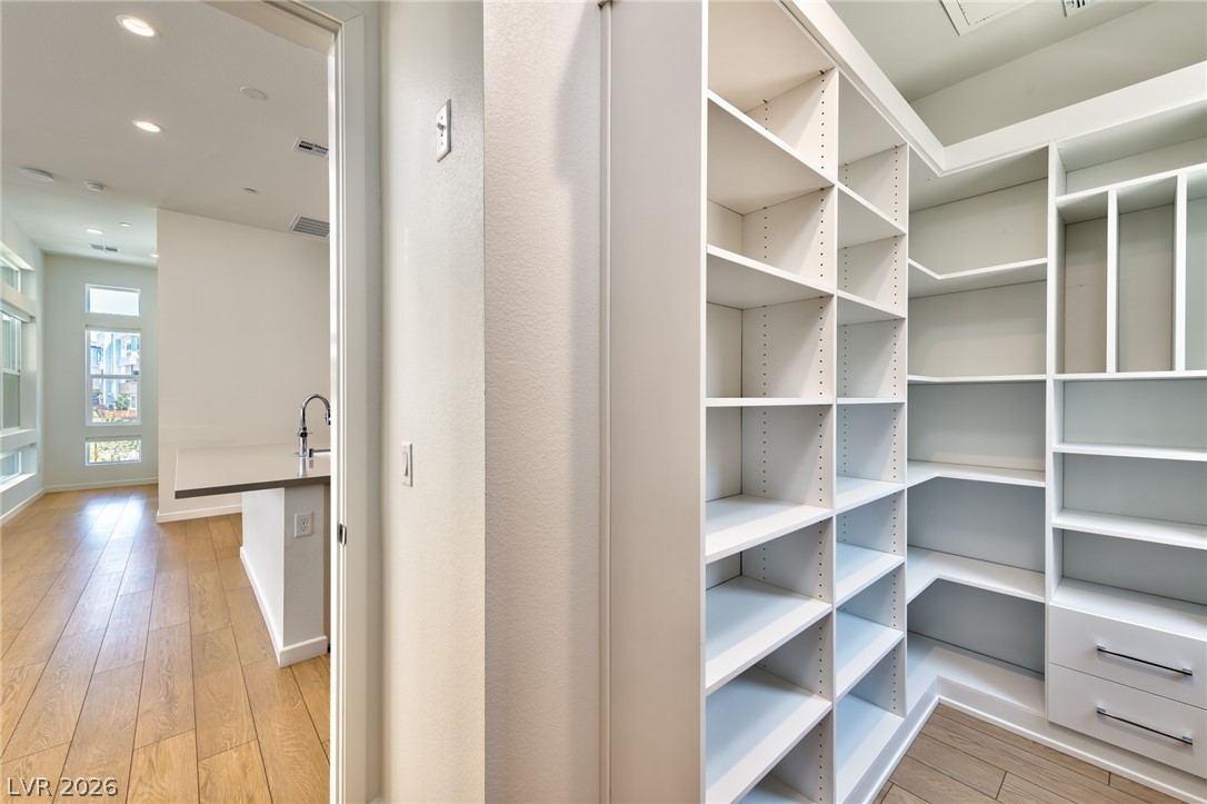 3327 Esker Rdg Avenue Henderson, NV 89044 - Photo 6 of 24 A glimpse into a spacious walk-in closet with ample shelving and a modern kitchen space.
