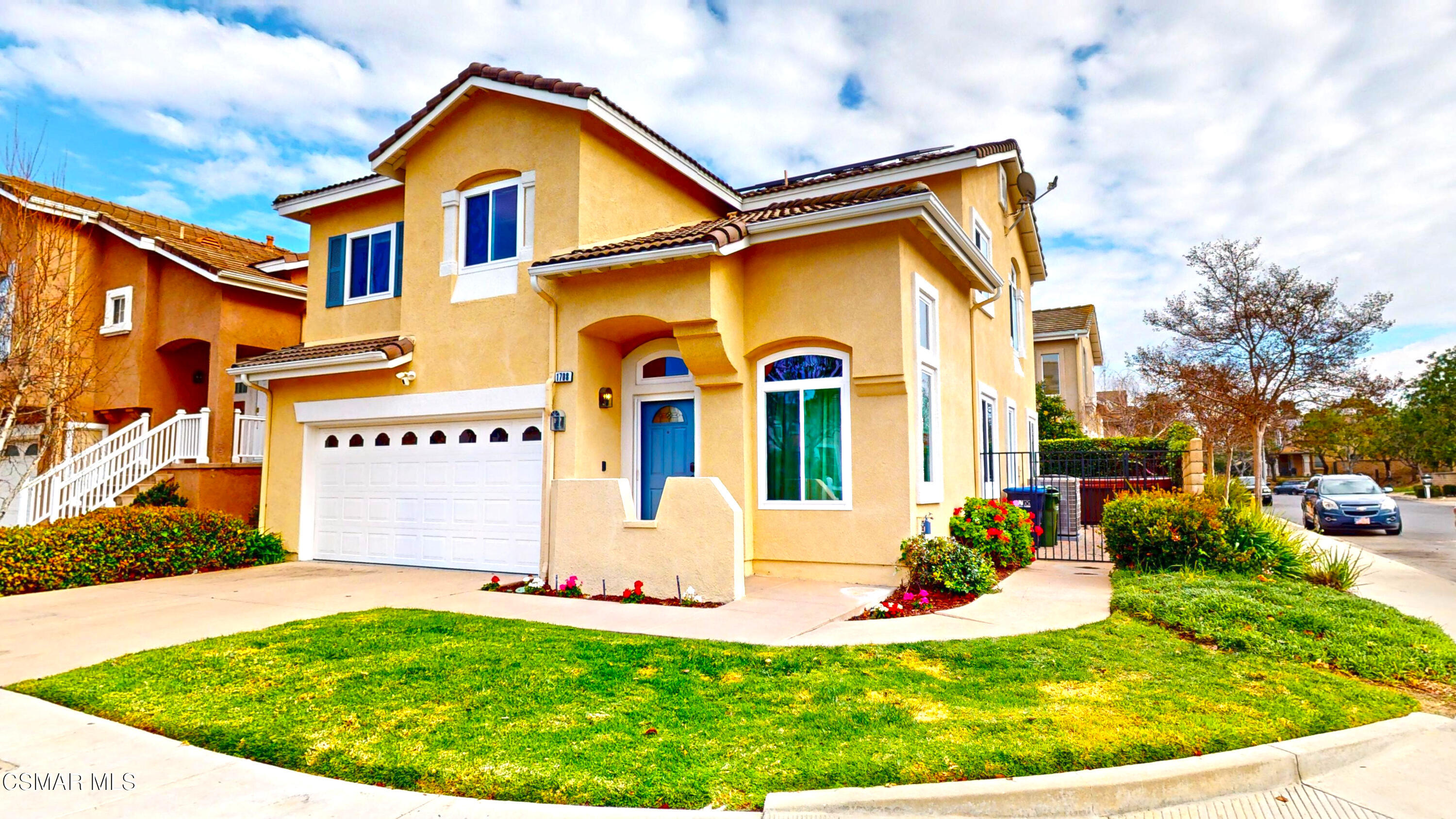 a view of a white house with a small yard and plants