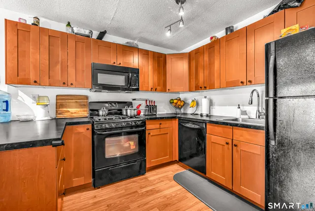 a kitchen with stainless steel appliances granite countertop wooden cabinets a stove top oven a sink and dishwasher