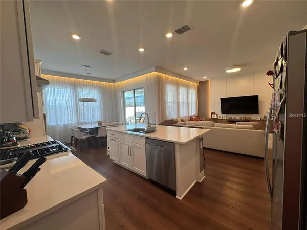 a kitchen with stainless steel appliances a sink a stove a refrigerator cabinets and living room view