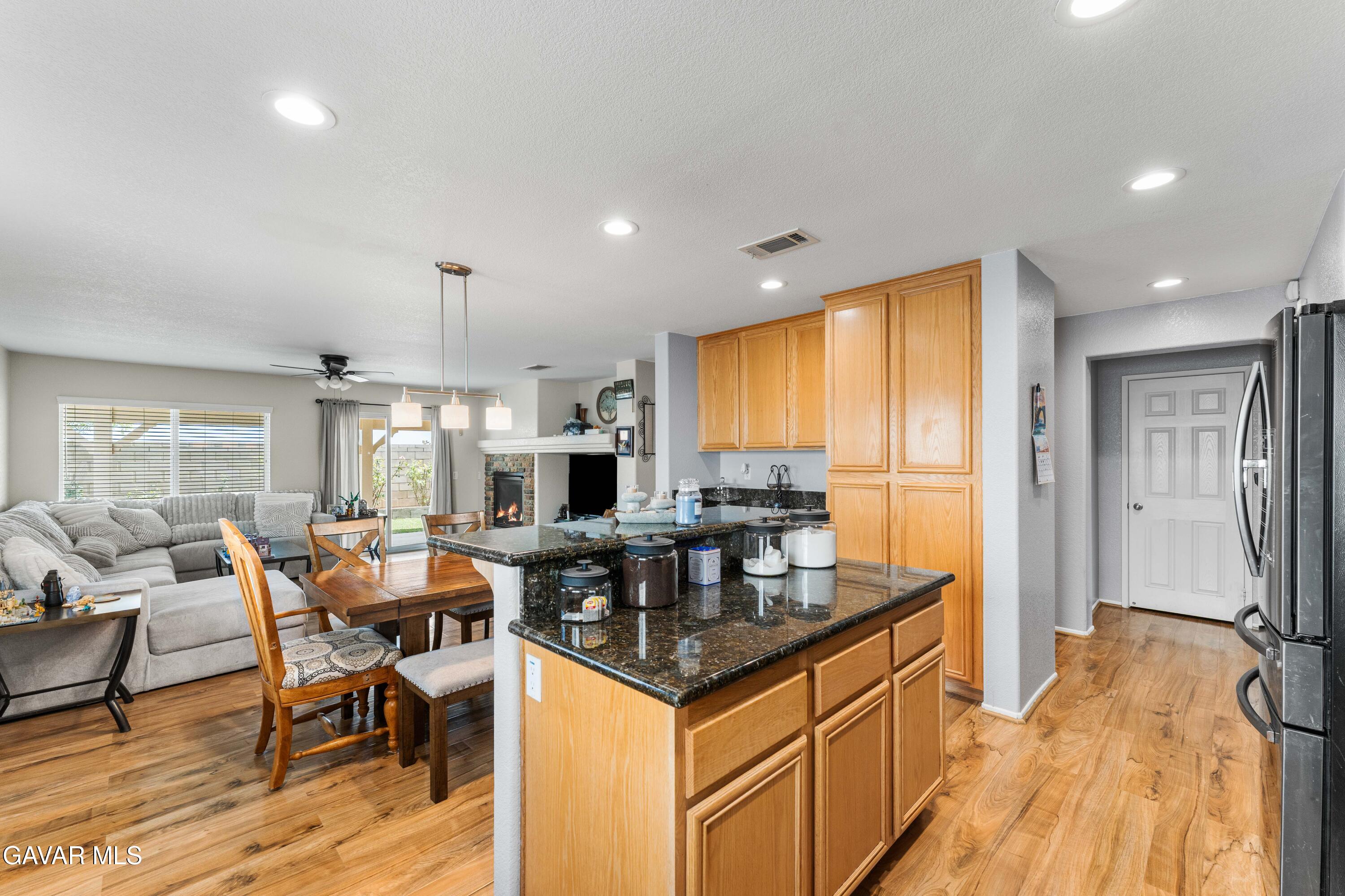 45448 Spahn Lane Lancaster, CA 93535 - Photo 11 of 49 a kitchen with granite countertop a table chairs stove a refrigerator and cabinets