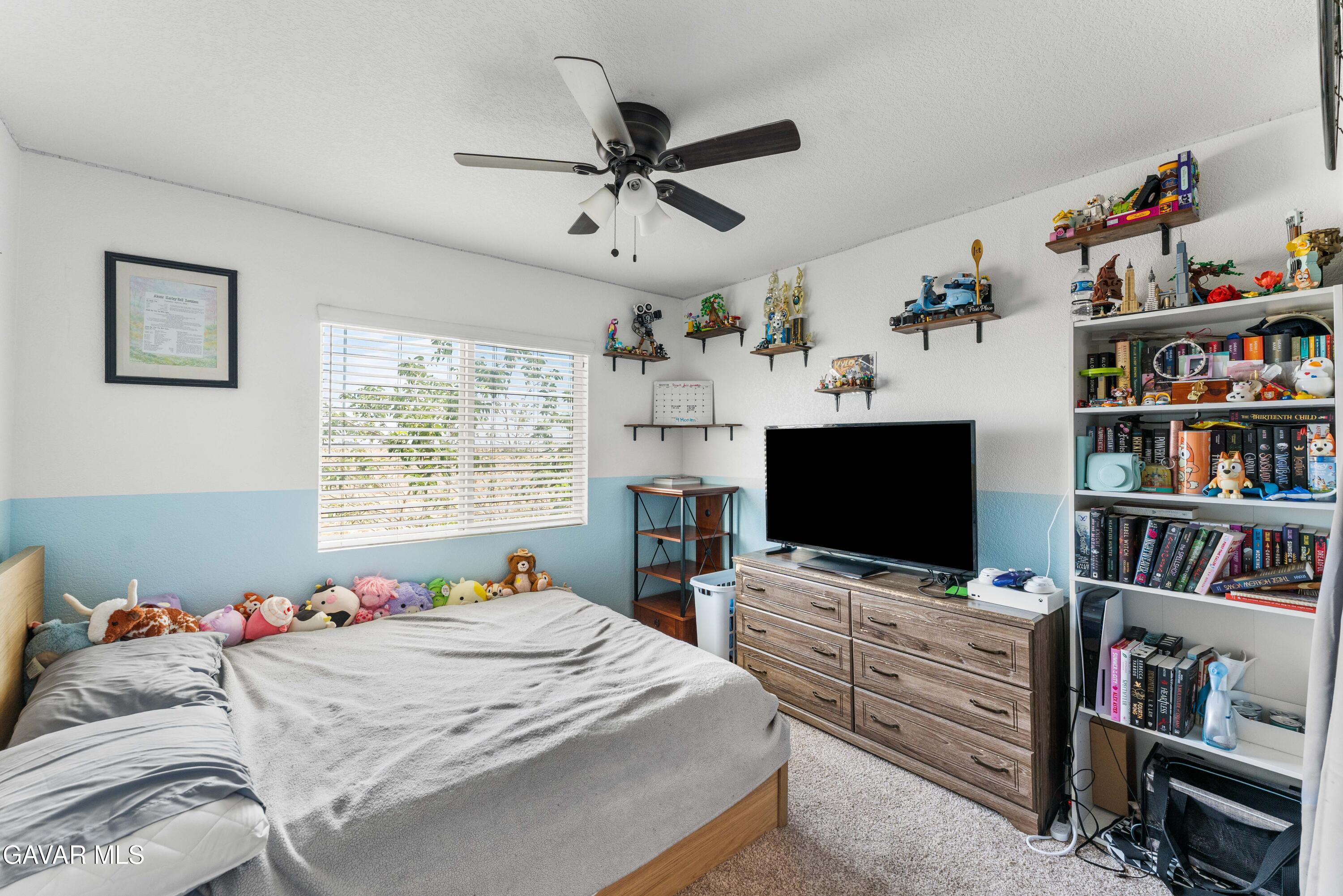 45448 Spahn Lane Lancaster, CA 93535 - Photo 30 of 49 a bedroom with a bed bookshelf and a flat screen tv