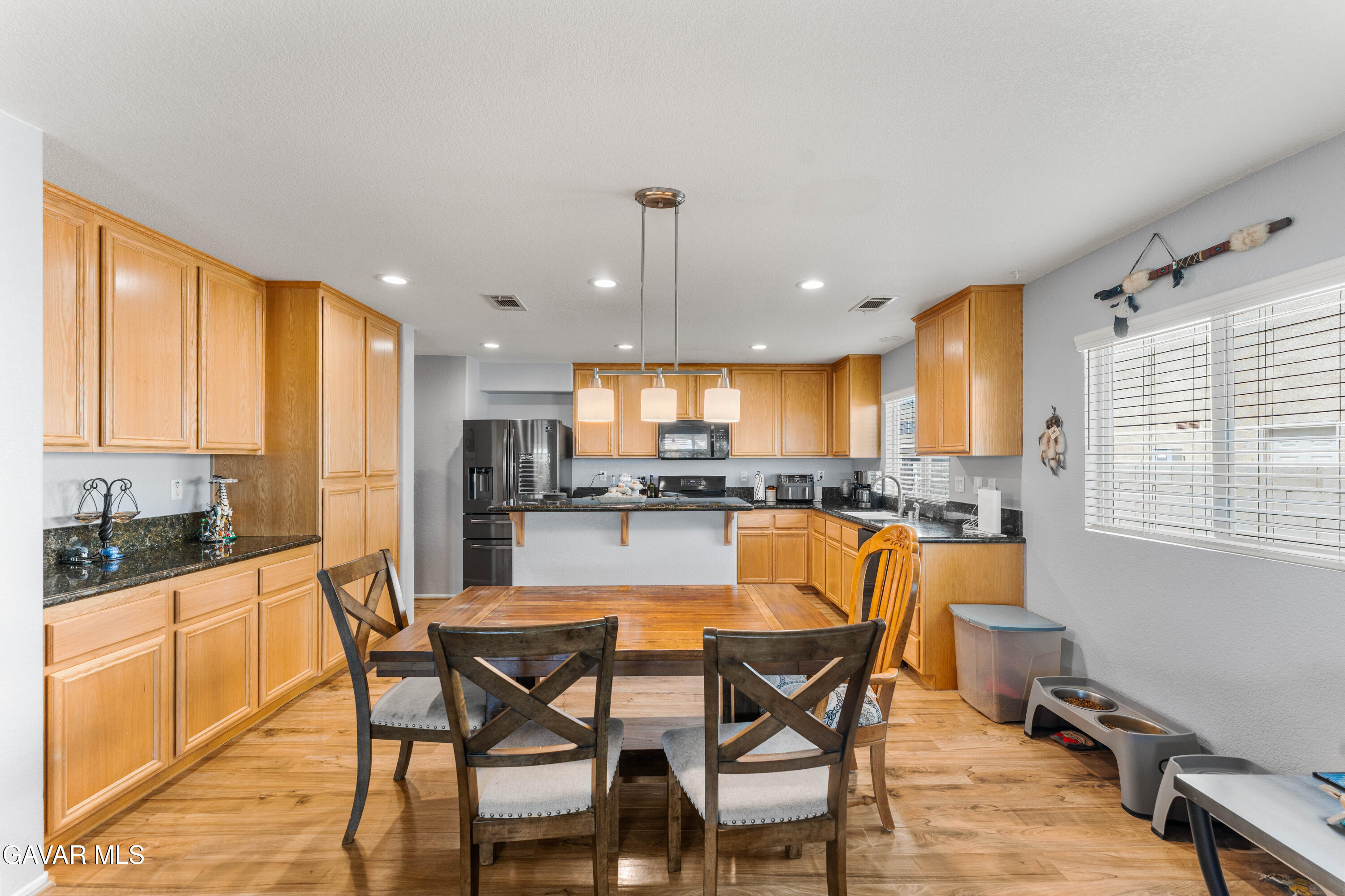 45448 Spahn Lane Lancaster, CA 93535 - Photo 7 of 49 a dining room with stainless steel appliances kitchen island granite countertop a table chairs and a refrigerator