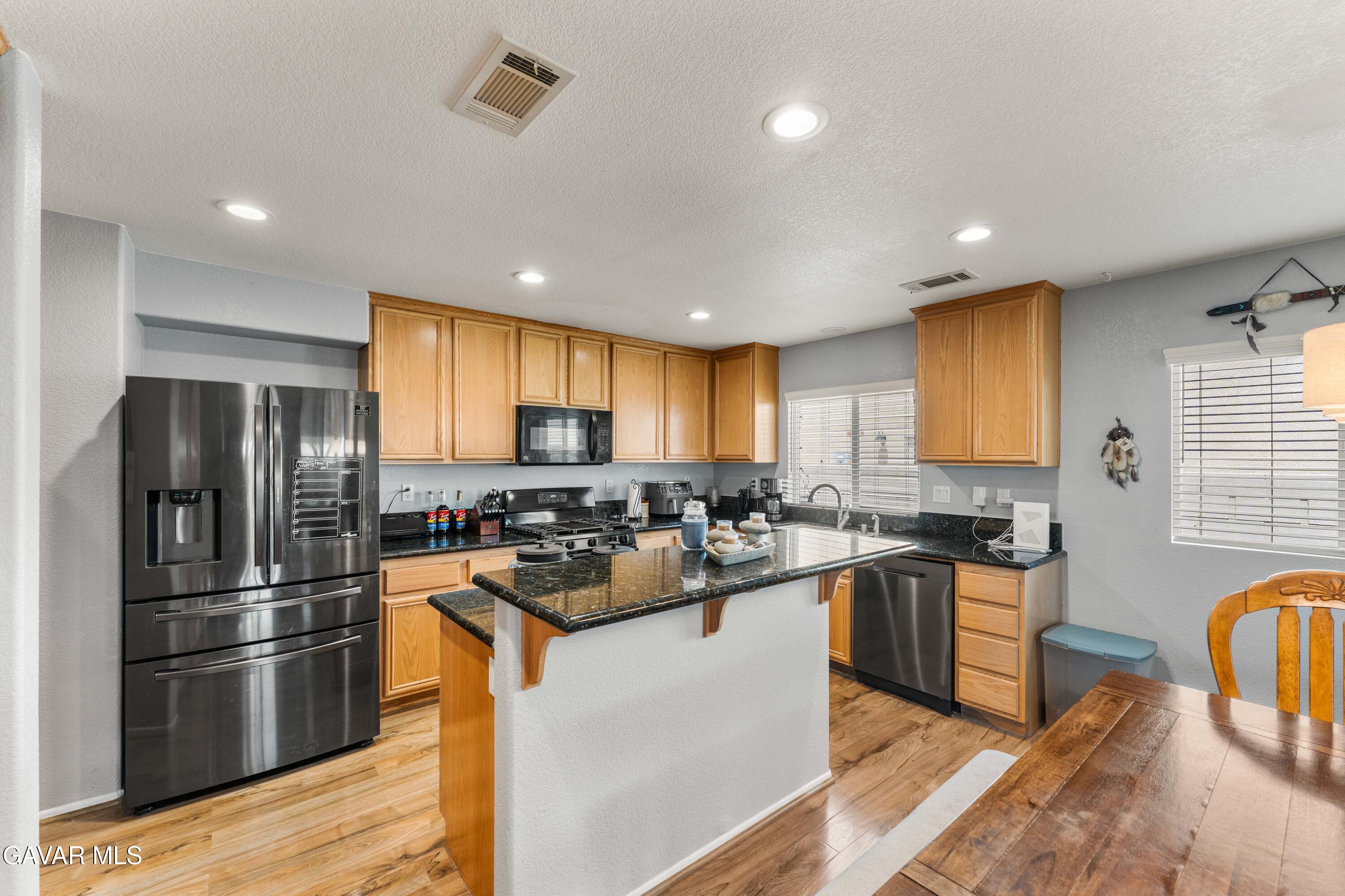 45448 Spahn Lane Lancaster, CA 93535 - Photo 8 of 49 a kitchen with refrigerator a stove a sink dishwasher and cabinets with wooden floor