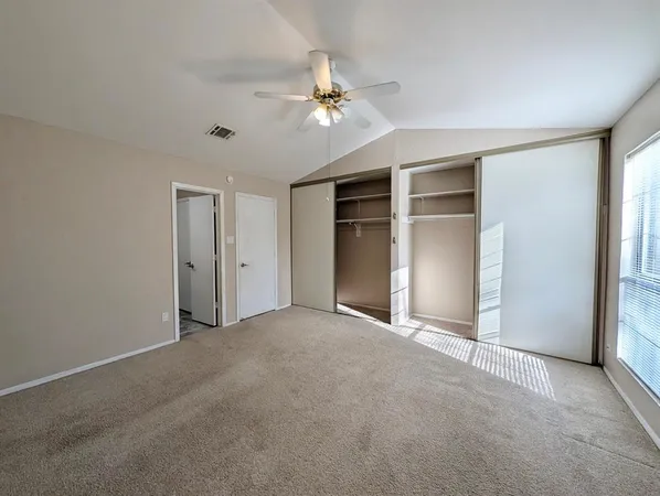 a view of an empty room with a ceiling fan and window