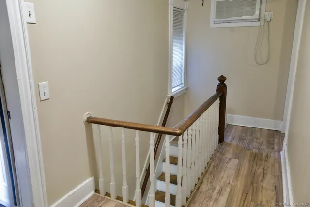 a view of a hallway with wooden floor and stairs