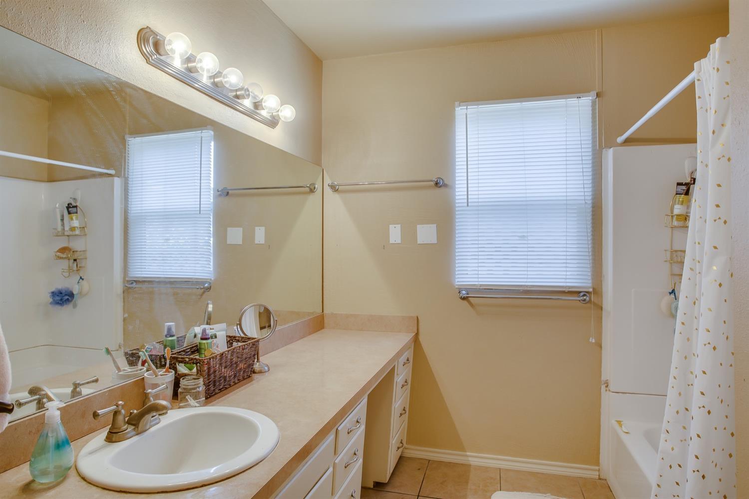 3114 30th Street Lubbock, TX 79410 - Photo 5 of 19 a bathroom with a sink a toilet and a mirror