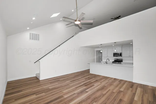 a view of a kitchen with wooden floor and a ceiling fan