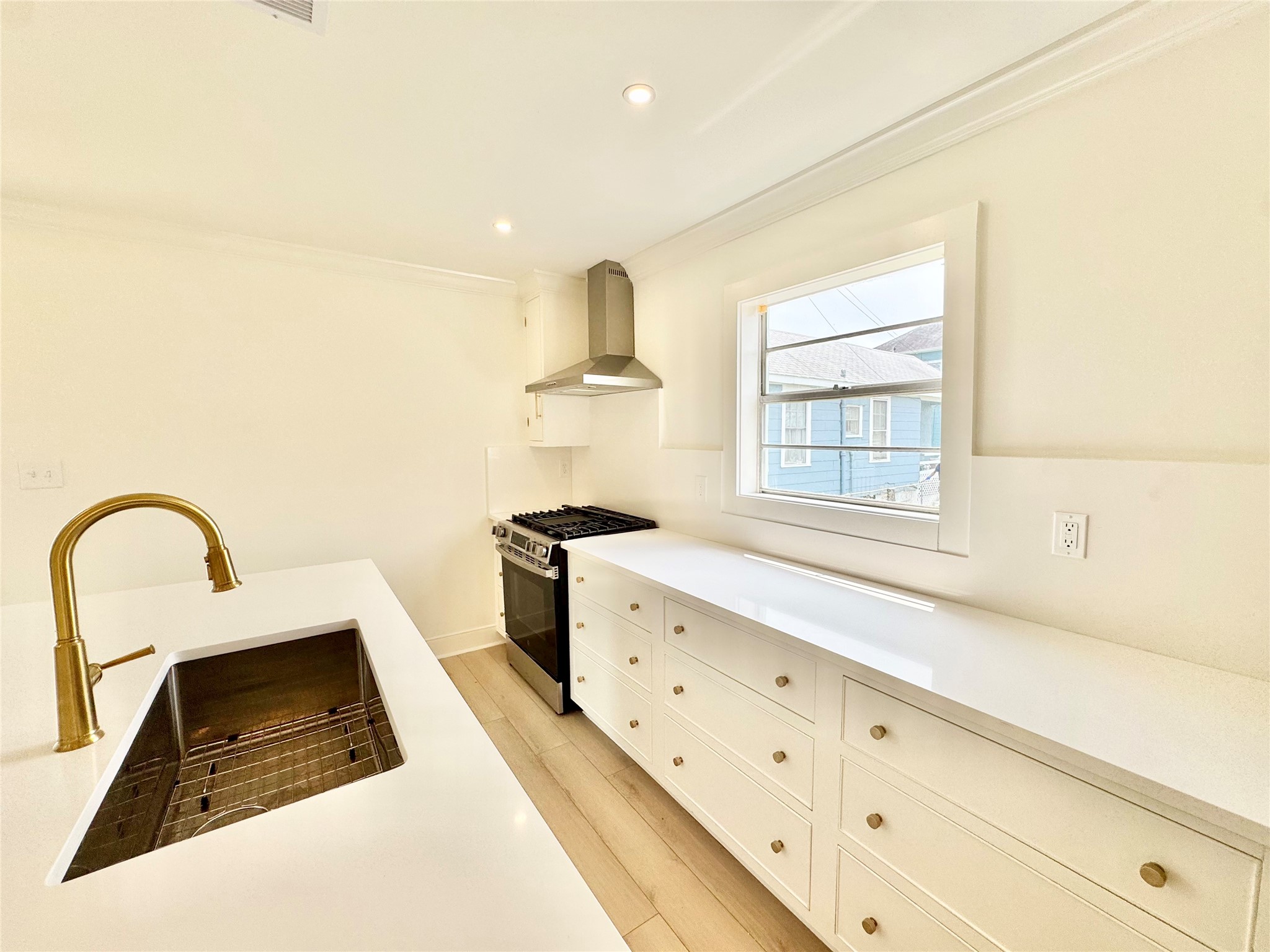 1312 35th Street Galveston, TX 77550 - Photo 13 of 32 a kitchen with granite countertop a sink a stove and a window