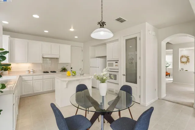 a kitchen with a dining table chairs wooden floor cabinets and stainless steel appliances