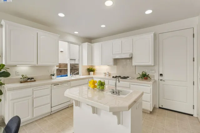 a kitchen with a sink white cabinets and stove