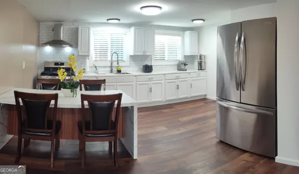 a kitchen with stainless steel appliances granite countertop a refrigerator a stove a sink dishwasher and a refrigerator with wooden floor