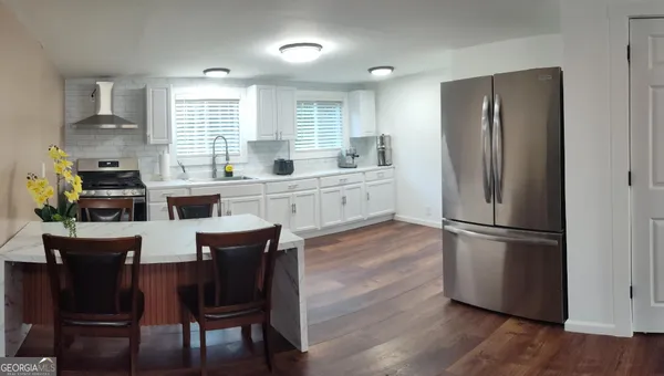 a kitchen with stainless steel appliances a dining table chairs stove refrigerator and cabinets