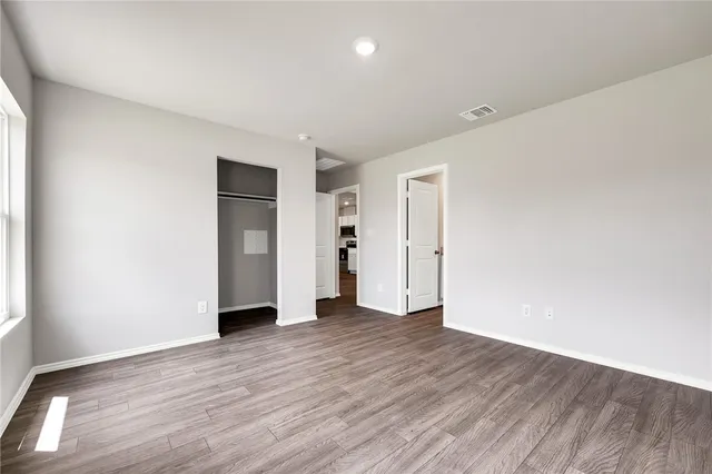 an empty room with wooden floor & windows and bathroom
