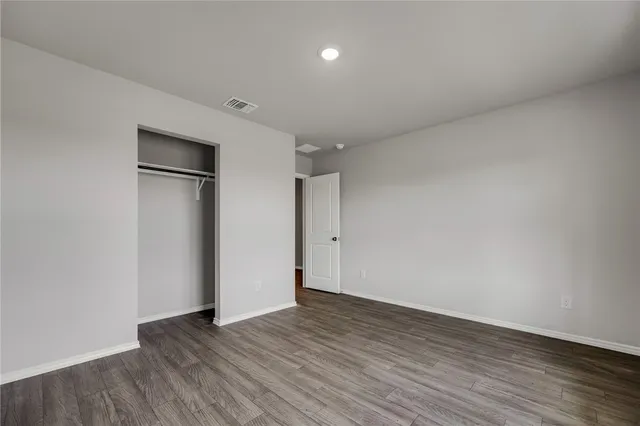 a view of an empty room with wooden floor and closet