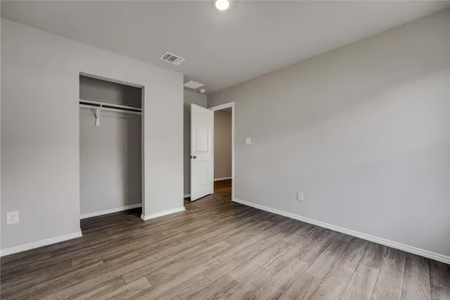 a view of an empty room with wooden floor and closet