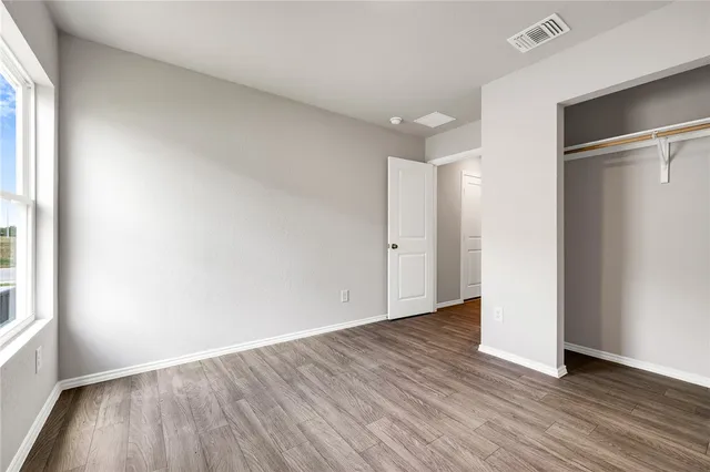 a view of an empty room with wooden floor window