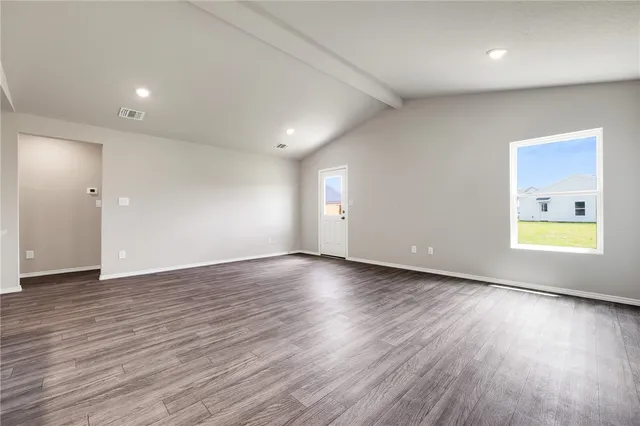 an empty room with wooden floor and window