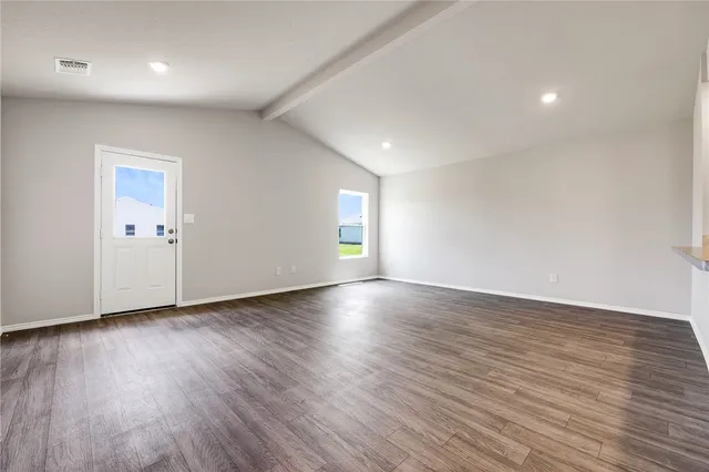 an empty room with wooden floor and natural light
