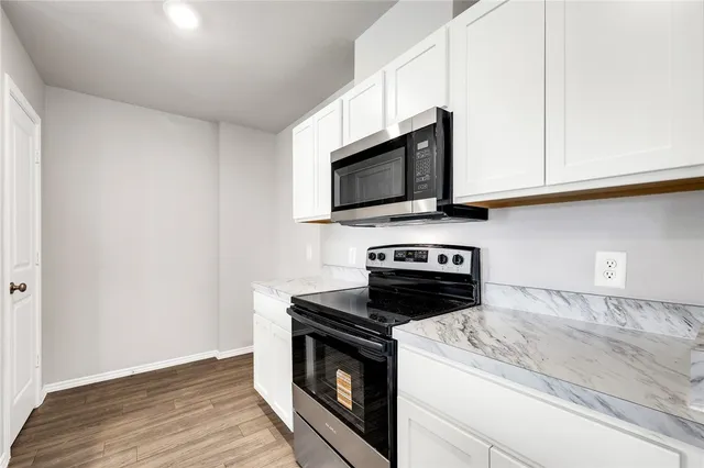 a kitchen with granite countertop cabinets stainless steel appliances and wooden floor