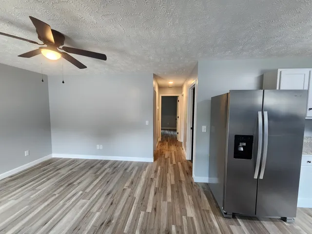 an empty room with wooden floor cabinet and windows