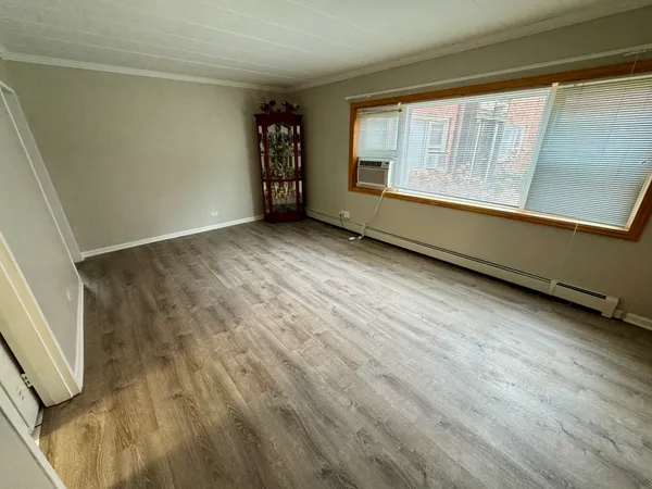 a view of an empty room with a window and wooden floor