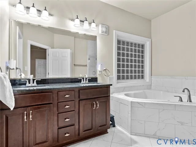 a bathroom with a granite countertop double vanity sink a mirror and a shower
