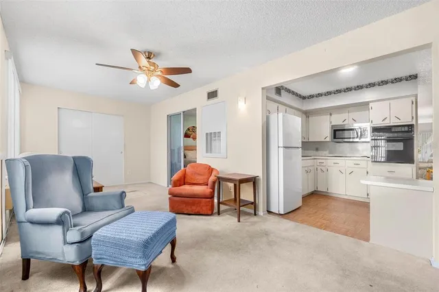 a living room with stainless steel appliances furniture and a chandelier