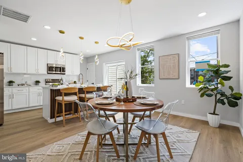 a kitchen with stainless steel appliances a sink a stove a refrigerator cabinets and dining table