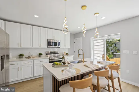 a kitchen with stainless steel appliances kitchen island granite countertop a refrigerator a sink dishwasher and white cabinets with wooden floor