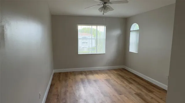 an empty room with windows and fan
