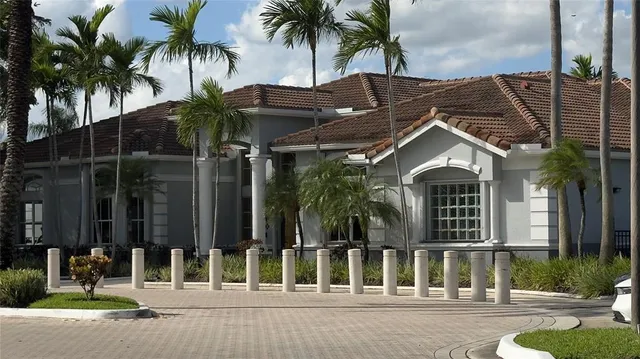 front view of house with a yard and palm trees