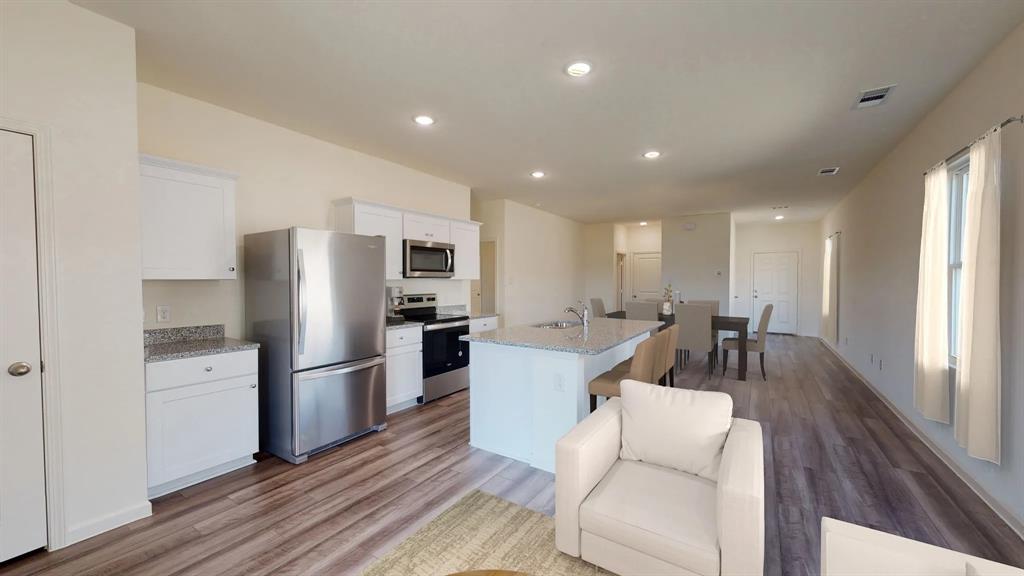 4508 Winecup Road Melissa, TX 75454 - Photo 2 of 14 Kitchen with stainless steel appliances, a center island with sink, white cabinets, light wood-type flooring, and recessed lighting