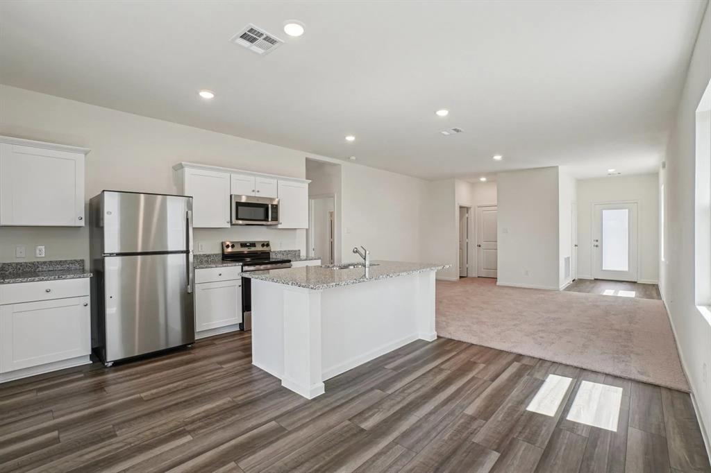 4508 Winecup Road Melissa, TX 75454 - Photo 4 of 14 Kitchen featuring stainless steel appliances, dark colored carpet, white cabinetry, light stone counters, and dark wood-style floors