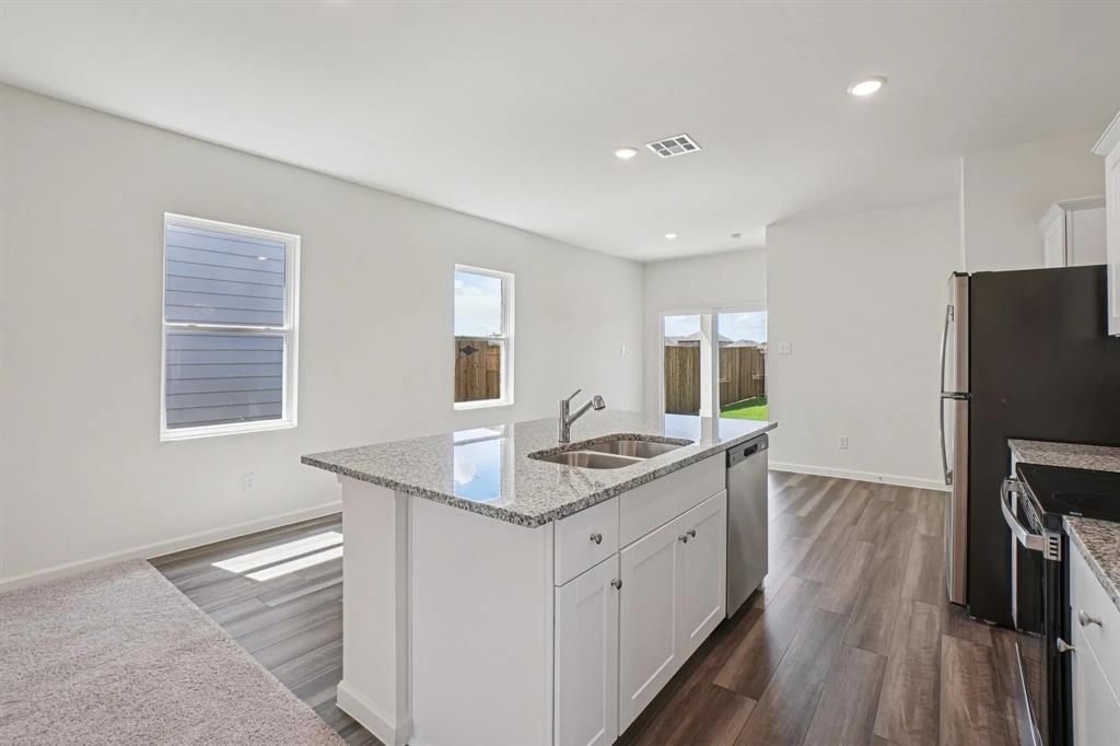 4508 Winecup Road Melissa, TX 75454 - Photo 5 of 14 Kitchen featuring white cabinets, light stone countertops, dark wood-style flooring, a center island with sink, and recessed lighting