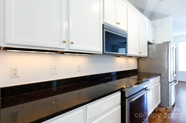 a kitchen with granite countertop white cabinets and black appliances
