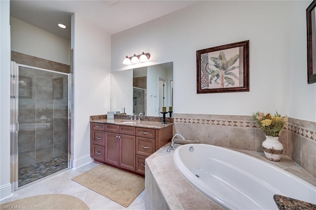 7587 Moorgate Point Way Naples, FL 34113 - Photo 39 of 50 Recessed lighting, glass-enclosed shower with tiled walls and flooring, dual sink vanity with granite countertop, built-in bathtub with tiled surround, and tiled flooring