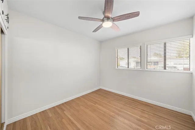 an empty room with wooden floor fan and windows