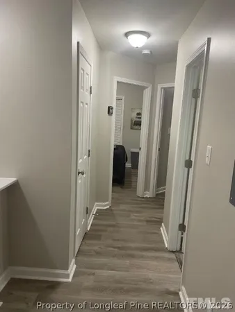 a view of a hallway with wooden floor and a bathroom