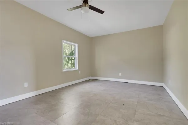 an empty room with a window and a ceiling fan