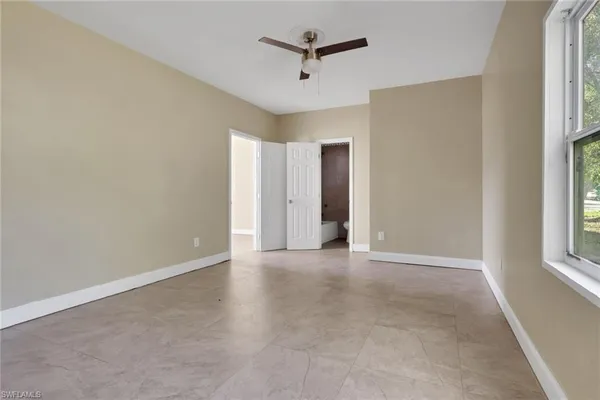 an empty room with windows and ceiling fan