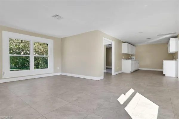 a view of empty room with a window and a kitchen